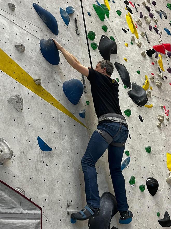 Gros plan sur un jeune homme en pleine progression verticale sur une voie d'escalade à Echandens.
